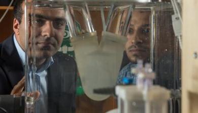 阿里·阿扎达尼和同事在阿扎达尼的实验室里观看生物医学设备