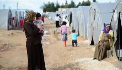 一名妇女抱着她的孩子站在土耳其的叙利亚难民营.